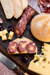 chopping board of cheeses and salami cold cuts of various varieties homemade country bread with almonds and handmade knife