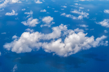 Fototapeta na wymiar White clouds against the blue of the Pacific Ocean seen from a plane near the Hawaiian Islands