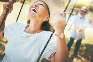 Woman, laugh and fun on swing in retirement, playful and energy in summer vacation for quality...