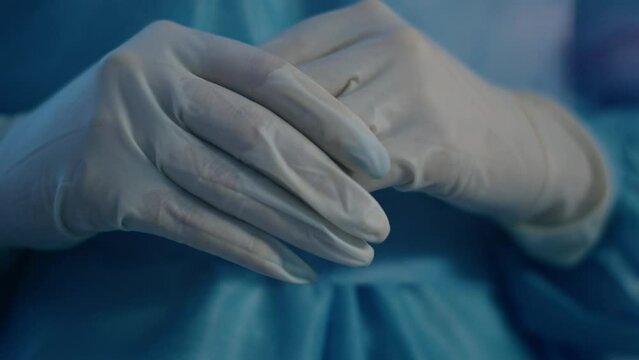 At the hospital closeup to the camera capturing details of a doctor full equipment with protective gloves closing hands