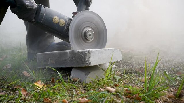 Men cuts concrete block with grinder and cutting plate, hard work