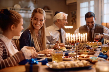 Happy Jewish woman talks to her daughter during family meal on Hanukkah.
