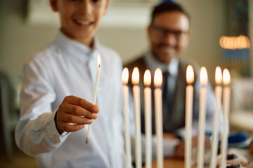 Close up of Jewish child lighting candles in menorah.