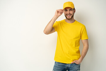 Delivery man in yellow uniform isolated on white background. Professional smiling confident male employee in cap, t-shirt courier dealer