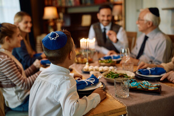 Rear view of Jewish boy having lunch with his extended family on Hanukah.
