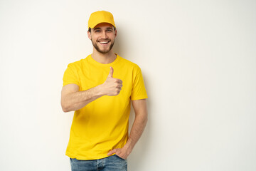 Delivery man in yellow uniform isolated on white background. Professional smiling confident male employee in cap, t-shirt courier dealer