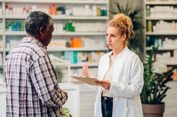 Fototapeta na wymiar Woman pharmacist talking with a senior patient customer in a pharmacy