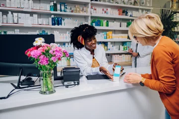 Wandcirkels aluminium Smiling african american woman pharmacist working at the counter in a pharmacy © Zamrznuti tonovi