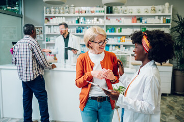 African american woman pharmacist talking to a senior customer in a pharmacy