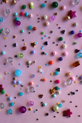 Various colorful beads on bright pink background. Top view.