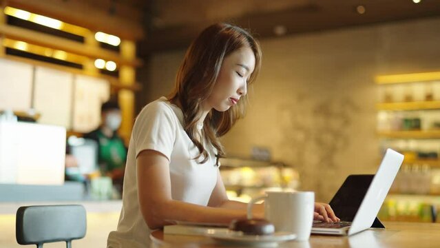 portrait of a beautiful Asian women watch digital class e-learning online for employee reskill upskill on notebook computer 
at home office workplace. Business school lesson education for adult people