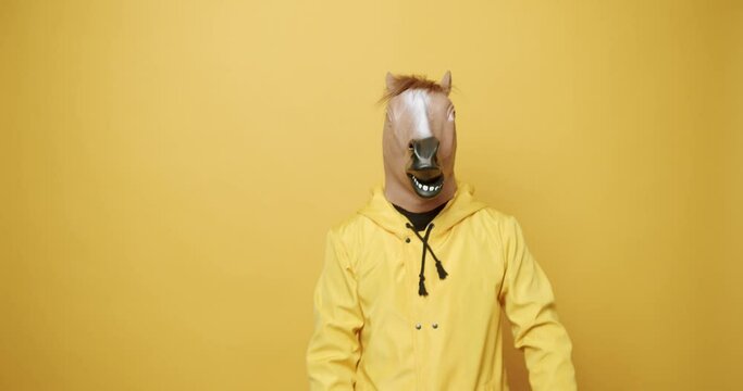 Man with horse mask making funny gestures. Funny Guy in Yellow Suits Dance with Horse Mask, Man having fun on isolated Yellow Background. Having Fun, Party Halloween. Fool's Day. Masquarade idea.