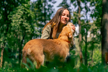 portrait of a young girl walking in the park with her dog, playing with a stick and teasing him with it