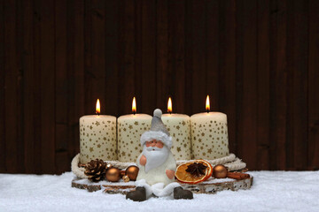 Vierter Advent: Zwei brennende Kerzen mit Zweigen, Weihnachtsmann und Christbaumkugeln vor einem...