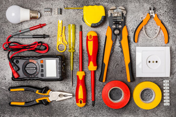 Electrician tools on background.Multimeter,construction tape,electrical tape, screwdrivers,pliers,an automatic insulation stripper, socket and LED lamp.Flatley.electrician concept.
