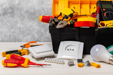 Electrician tools on background.Multimeter,construction tape,electrical tape, screwdrivers,pliers,an automatic insulation stripper, socket and LED lamp.Flatley.electrician concept.