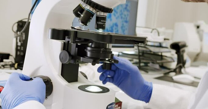 Male doctor using microscope in laboratory. Using a microscope to examine the patients blood health condition. Medical device. Examining blood under the high-tech microscope equipment.