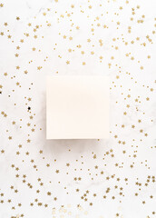 White blank paper square card mockup and golden various sizes stars confetti on white Christmas background