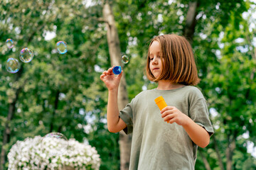 portrait beautiful cute little girl blowing soap bubbles in city park happy carefree childhood