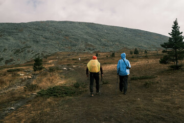  active lifestyle.A man with a tourist backpack and a photographer girl go to the top of the mountain.Hiking in the mountains