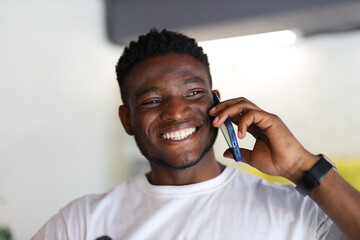 A confident and happy African American man with a cheerful smile talking on his smartphone.