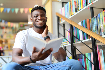 A happy young student in a university library, surrounded by books on bookshelves, finds joy in knowledge.