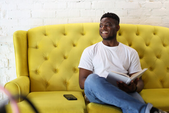 A confident African American man enjoying some leisure time at home, using a laptop and a smartphone.