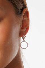 Beautiful young girl with fresh healthy skin. Woman advertise ear-rings. White background. Earrings, ear caffs closeup. Blond european woman with long hair with big lips, pretty smile. Cosmetology