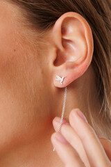 Obraz premium Beautiful young girl with fresh healthy skin. Woman advertise ear-rings. White background. Earrings, ear caffs closeup. Blond european woman with long hair with big lips, pretty smile. Cosmetology