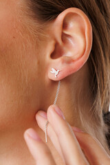 Beautiful young girl with fresh healthy skin. Woman advertise ear-rings. White background. Earrings, ear caffs closeup. Blond european woman with long hair with big lips, pretty smile. Cosmetology