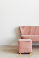 Minimalist composition of room interior with pink pouf and sofa against white wall, copy space