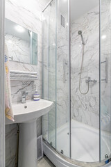 A simple bathroom with a silver shower, a square mirror and classic white tiles