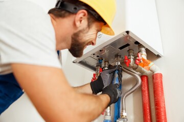Closeup of plumber using screwdriver while fixing boiler or water heater, working on heating system...