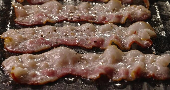 Frying halal beef bacon in pan side view close up. Pan-fried bacon slices capture the essence of sizzling goodness, ready to be devoured with delight. Juicy halal beef bacon flavorful and satisfying