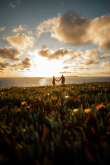Slhouette of a couple at sunset, woman and man walking along seashore in rays of sunset sunlight. walk and hug. place for text, romantic relationships, freedom and carelessness
