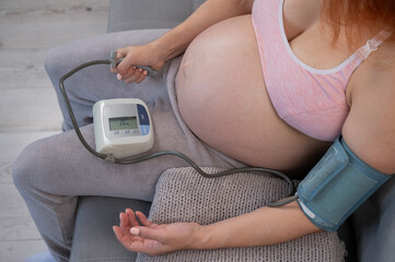 Close-up of the belly of a pregnant woman measuring blood pressure with a tonometer. Hypotension. 