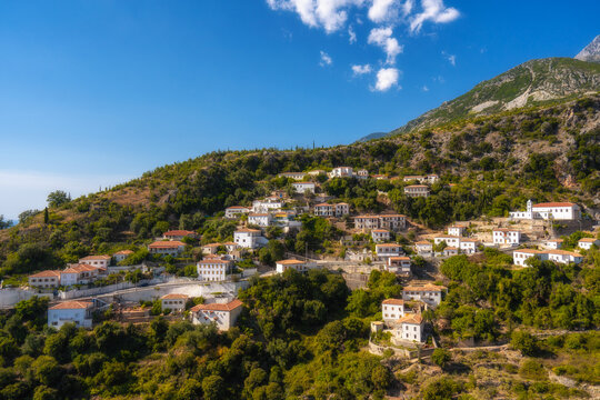 View of white houses with yellow shutters, moutains and sea. Vuno, Albania.