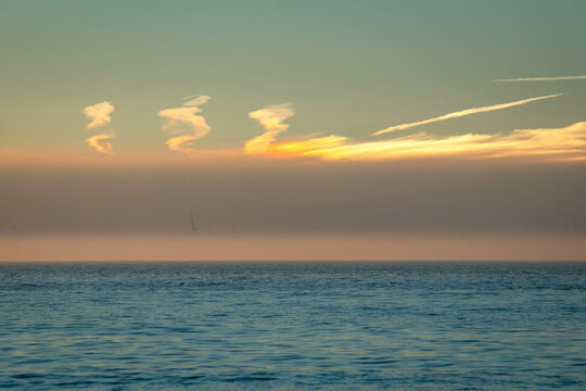 Clouds over the North Sea during a colorful sunset where a sundog or parhelia is visible in the clouds