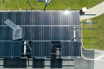 Failing of photovoltaic technology integrated in urban infrastructure. Hurricane wind damage to solar panels installed as shade roof over parking lot for parked electric cars