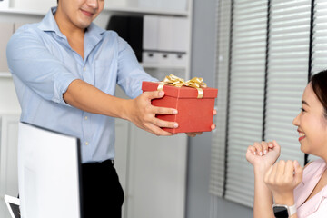 Asian businessman giving a gift box to a coworker in the office setting environment. Thank you and success celebration in the corporate business office concept. - 660067131