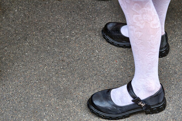 Legs of a schoolgirl in white tights and black shoes