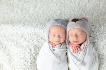 portrait of twins in identical hats, newborn boys, twins. newborn photo session. children brothers on white background