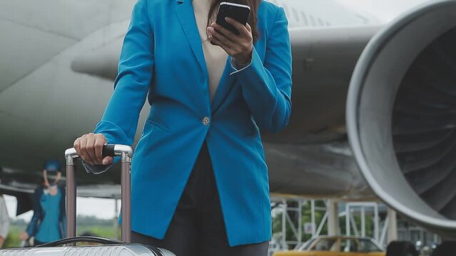 businesswoman hand holding tablet while carrying luggage with airport background