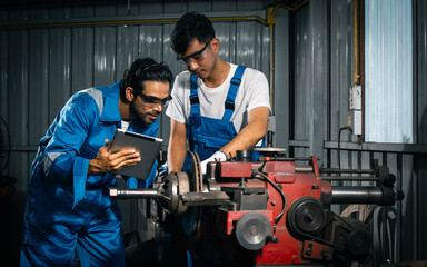 Fototapeta na wymiar Two adult handsome male mechanics wearing uniform, using machine for fix, repair car or automobile components, teamwork helping, working in car maintenance service center or shop. Industry Concept.