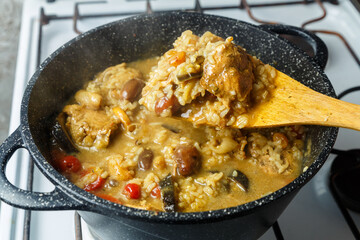 Braised eggplants with meat and rice in spices with dogwood in an Israeli style in a cast-iron high frying pan with a wooden spatula.