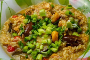 Braised eggplant with meat and rice with dogwood in Israeli style in a plate sprinkled with green onions on the table.
