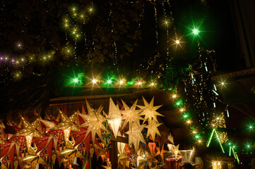 Ornaments of lights and glittering stars at a Christmas market at Christmas night.