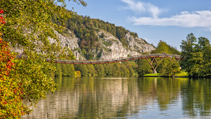 Fototapeta premium the famous pedestrian wooden bridge tatzlwurm over the rhine-main-danube canal with hikers in sunlight and autumnal trees