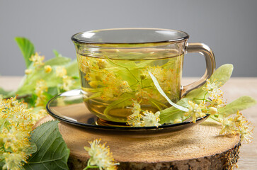 Tilia platyphyllos known as large-leaved linden herbal tea made out of an freshly picked blossoms with tree leaves and branches with blossoms for decoration on home wood table. Studio back light.