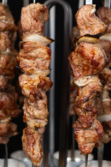 Cooking pork meat in an electric kebab maker on vertical skewers